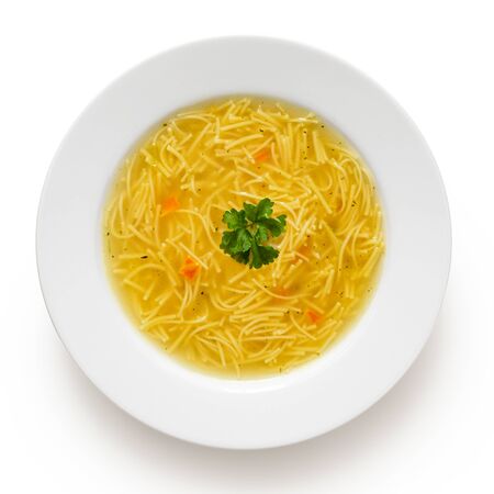 Instant chicken noodle soup in a white ceramic soup plate isolated on white. Top view. Parsley garnish.の写真素材