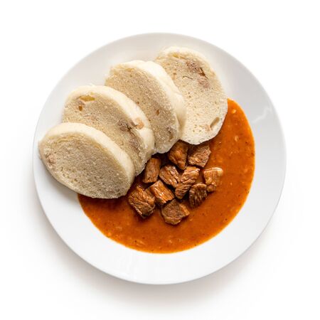 Beef goulash with bread dumplings on white ceramic plate isolated on white. Top view.の写真素材