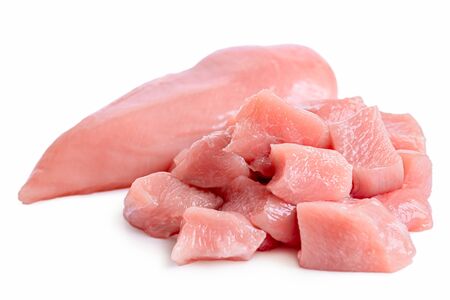 A pile of cut up uncooked boned chicken breast next to whole chicken breast isolated on white.の写真素材