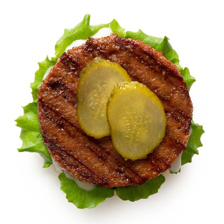 Freshly grilled plant based burger patty on bun with lettuce, slices of gherkin and sauce isolated on white. Top view.の写真素材