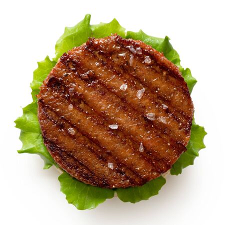 Freshly grilled plant based burger patty on bun with lettuce and rock salt isolated on white. Top view.の写真素材