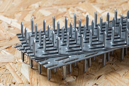 Two galvanized nail plates lying on chip board. Blurred background.の写真素材