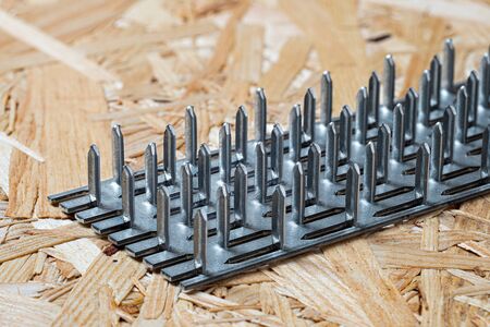 A galvanized nail plate lying on chip board. Blurred background.の写真素材