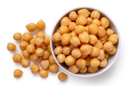 Cooked chick peas in a white ceramic bowl isolated on white. Spilled chick peas. Top view.の写真素材