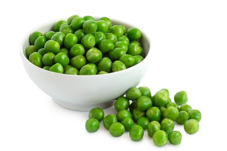 Fresh green garden peas in a white ceramic bowl isolated on white. Spilled peas.の写真素材