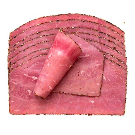 A rolled slice of pastrami on top of arranged slices of pastrami isolated on white. Top view.の写真素材