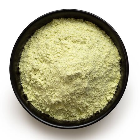 Dried green pea flour in a black ceramic bowl isolated on white. Top view.の写真素材