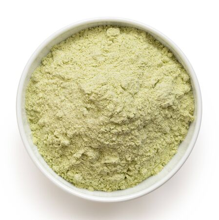 Dried green pea flour in a white ceramic bowl isolated on white. Top view.の写真素材