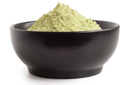 Dried green pea flour in a black ceramic bowl isolated on white. Low angle.の写真素材