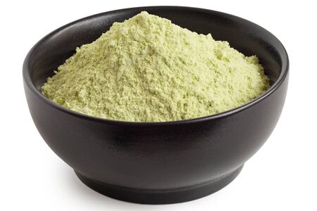Dried green pea flour in a black ceramic bowl isolated on white. High angle.の写真素材