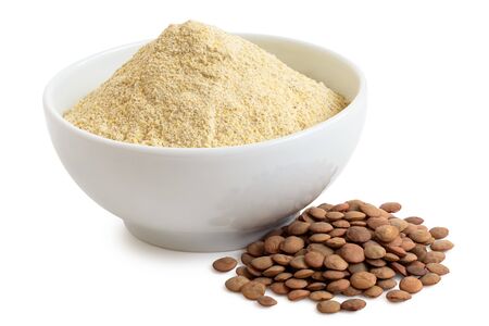 Dried lentil flour in a white ceramic bowl next to a pile of brown lentils isolated on white.の写真素材