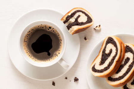 Cup of black coffee with slices of Czech poppy seed strudel on white. Top view.
