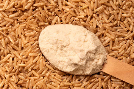 Heaped spoon of brown rice flour on top of brown rice. Top view. Background.の写真素材