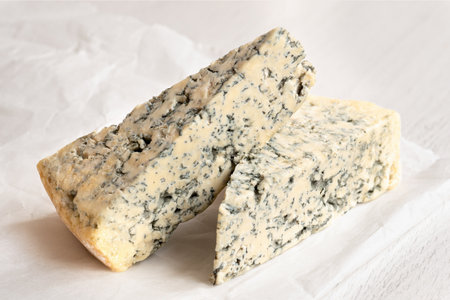 Two blue cheese wedges on white wax paper.の写真素材