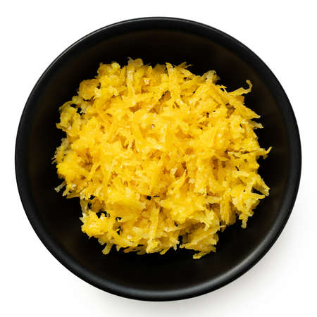 Freshly grated lemon zest in a black ceramic bowl isolated on white. Top view.の写真素材