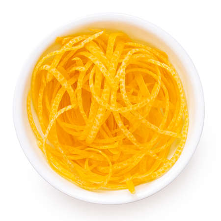 Freshly peeled lemon zest in a white ceramic bowl isolated on white. Top view.の写真素材