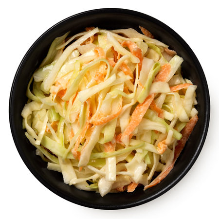 Coleslaw in a black ceramic bowl isolated on white. Top view.の写真素材