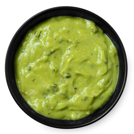 Guacamole dip in a black ceramic bowl isolated on white. Top view.の写真素材