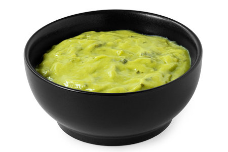 Guacamole dip in a black ceramic bowl isolated on white.の写真素材