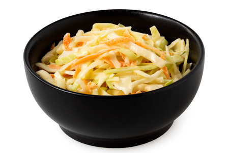 Coleslaw in a black ceramic bowl isolated on white.の写真素材