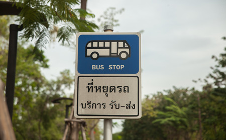 Bus stop sign on pole next to the roadの写真素材