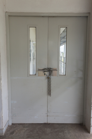 Padlock and metal chain on a metal doorの写真素材
