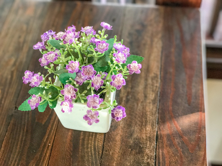 Plastic rose in vase on wooden tableの写真素材