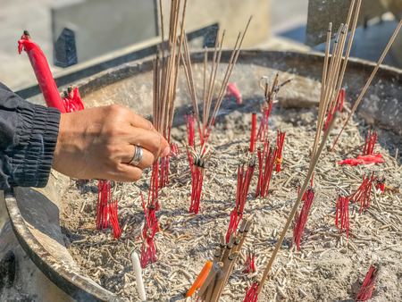 Hand put incense stick in to the pot の写真素材