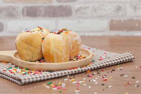 a variety of jam doughnut on wooden plate with sprinklesの写真素材
