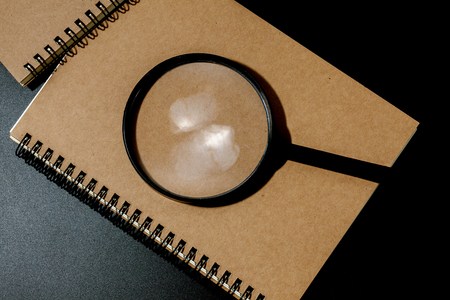 magnifying glass and notebook on black background, investigate conceptの写真素材