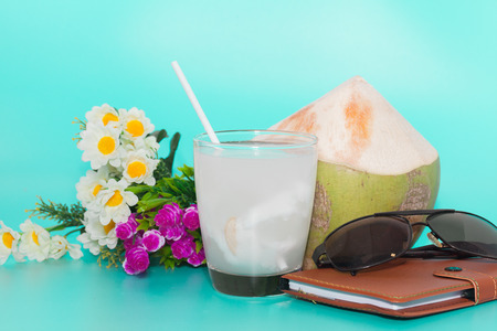 coconut with drinking straw, notebook and sunglasses on blue backgroundの写真素材