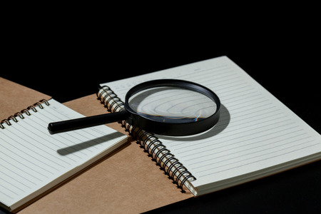 magnifying glass and notebook on black background, investigate conceptの写真素材