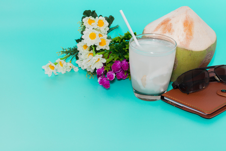 coconut with drinking straw, notebook and sunglasses on blue backgroundの写真素材