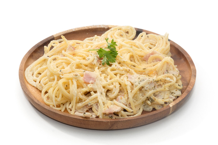 spaghetti carbonara with cream on wooden plate on white backgroundの写真素材