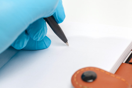 Hand in blue glove write on empty bookの写真素材