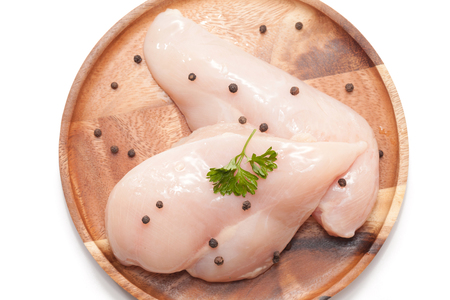 Raw chicken breast,peppers and parsley on wooden plateの写真素材