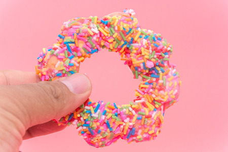 hand holding Fried Donuts on pink backgroundの写真素材
