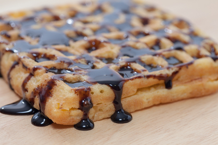 Waffles with melted chocolate on wooden plateの写真素材