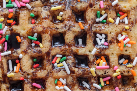 Waffles with melted chocolate and colorful sparkle on wooden plateの写真素材