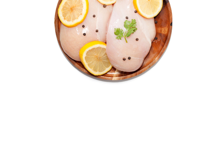 raw chicken breast, lemon, pepper on wooden plate on white backgroundの写真素材