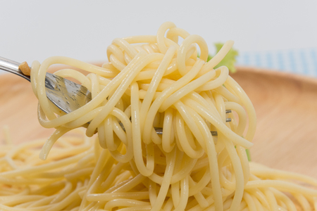 spaghetti without sauce with fork on wooden plateの写真素材