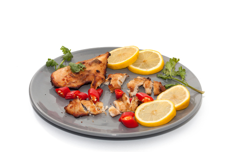 Roast chicken with chilli, lemon on grey plateの写真素材