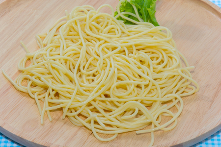 spaghetti without sauce with fork on wooden plateの写真素材