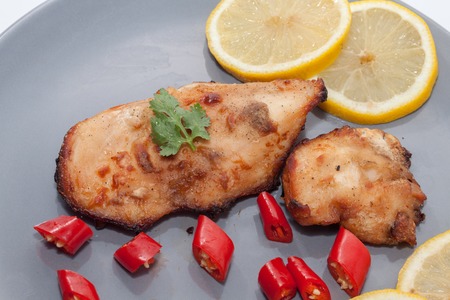 Roast chicken with chilli, lemon on grey plateの写真素材