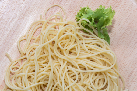 spaghetti without sauce with fork on wooden plateの写真素材