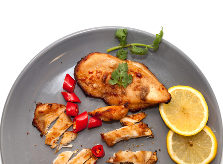 Roast chicken with chilli, lemon on grey plateの写真素材
