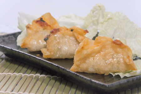 fried pork gyoza dumplings on black plateの写真素材