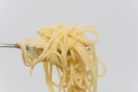 spaghetti without sauce with fork on wooden plateの写真素材