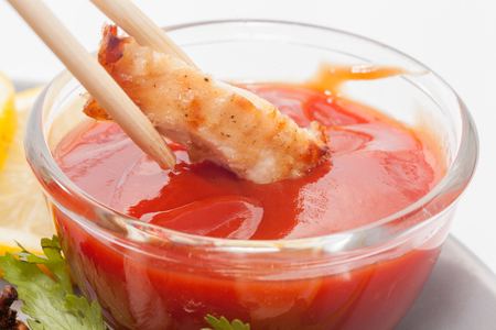 close up of chopstick and chicken breast with sauceの写真素材