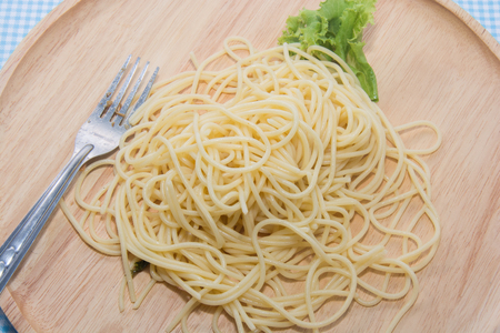 spaghetti without sauce with fork on wooden plateの写真素材